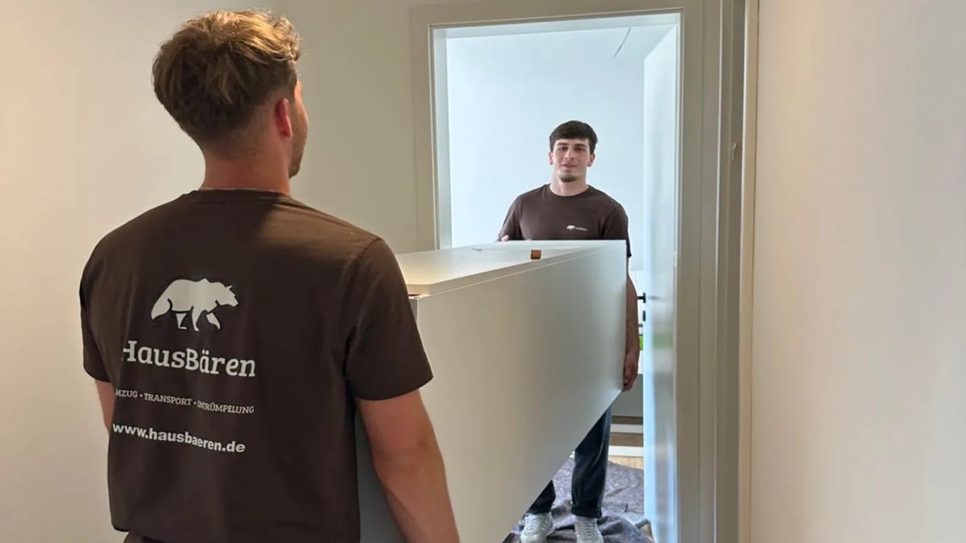 HausBären-Mitarbeiter beim Möbeltransport, von hinten mit gut sichtbarem Firmenlogo