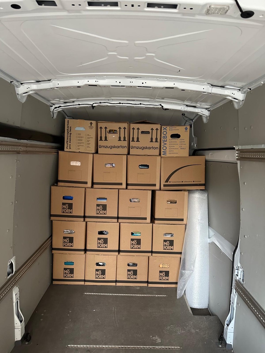 Sorgfältig gestapelte Umzugskartons und geschützte Möbel im Transporter
